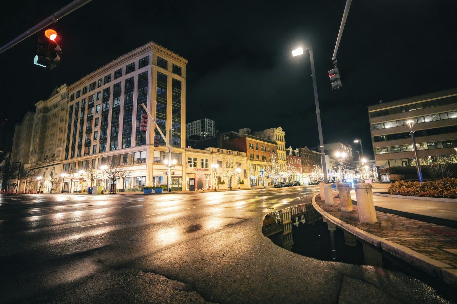 A person walking down a quiet, rain-slicked city street at night