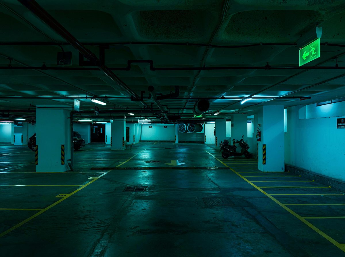 A quiet parking lot illuminated by a single overhead light at night