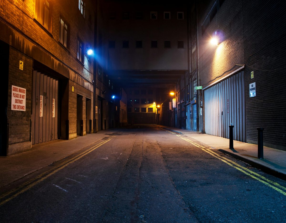 An empty city street at night lit by a single streetlamp